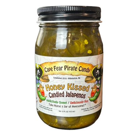 A glass jar of Cape Fear Pirate Candy's Honey Kissed Candied Jalapeños, filled with green jalapeño peppers in honey and topped with a black metal screw lid, shown against a plain white background.