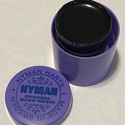Nyman Harts Original Bass Rosin with a purple container and matching lid on a light gray background.